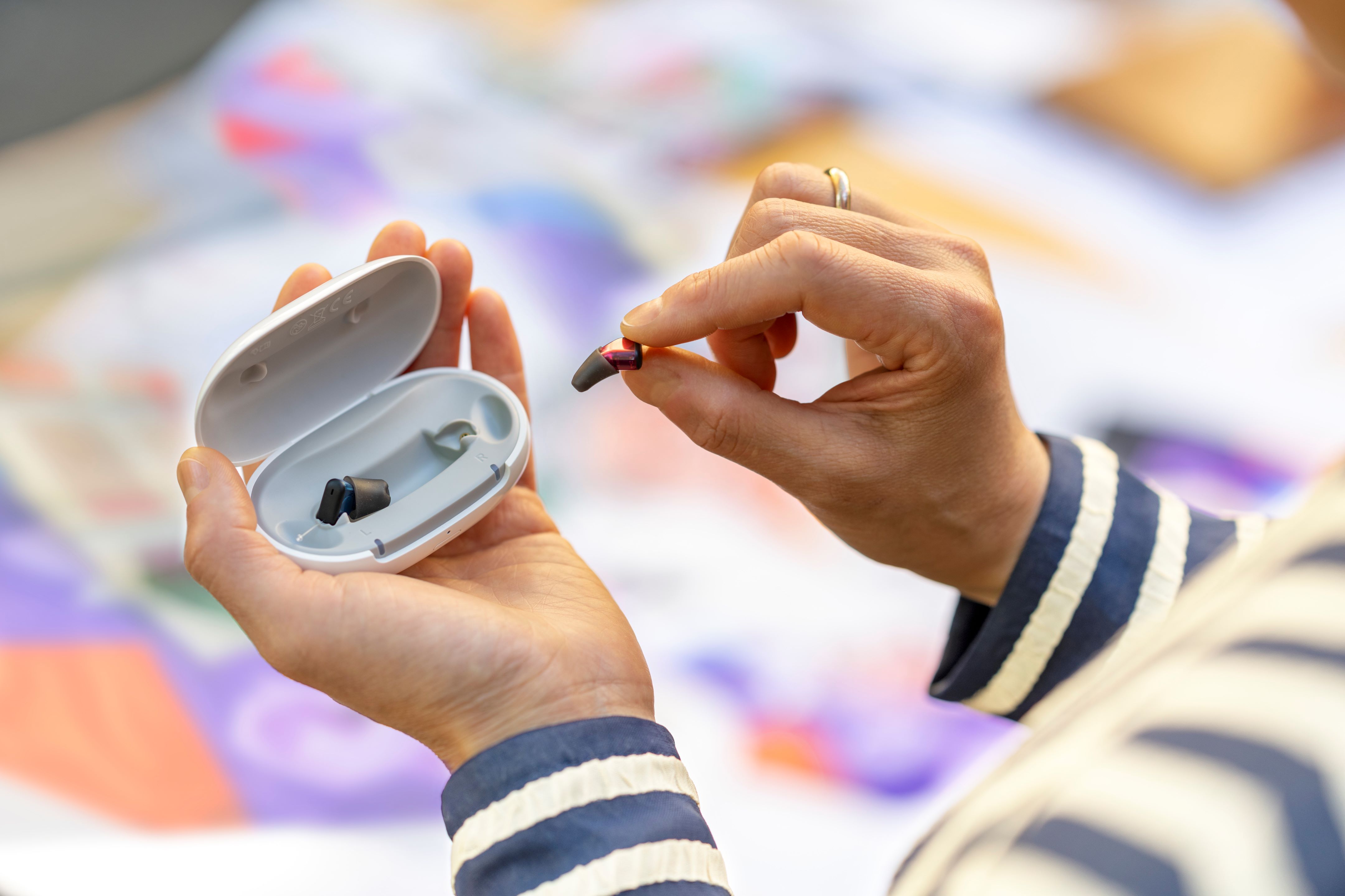 Person holding hearing aid case and removing a hearing aid